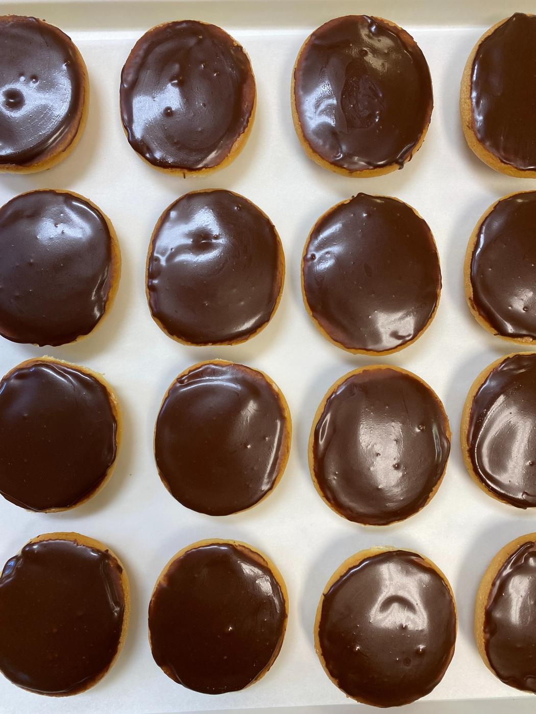 A tray of chocolate drops, glossy dark chocolate over a soft cookie